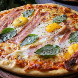 Delicious gourmet pizza topped with ham, eggs, and fresh basil leaves, perfect for a culinary delight.