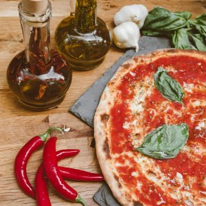 Delicious Italian pizza with fresh basil and olive oil on a wooden table.